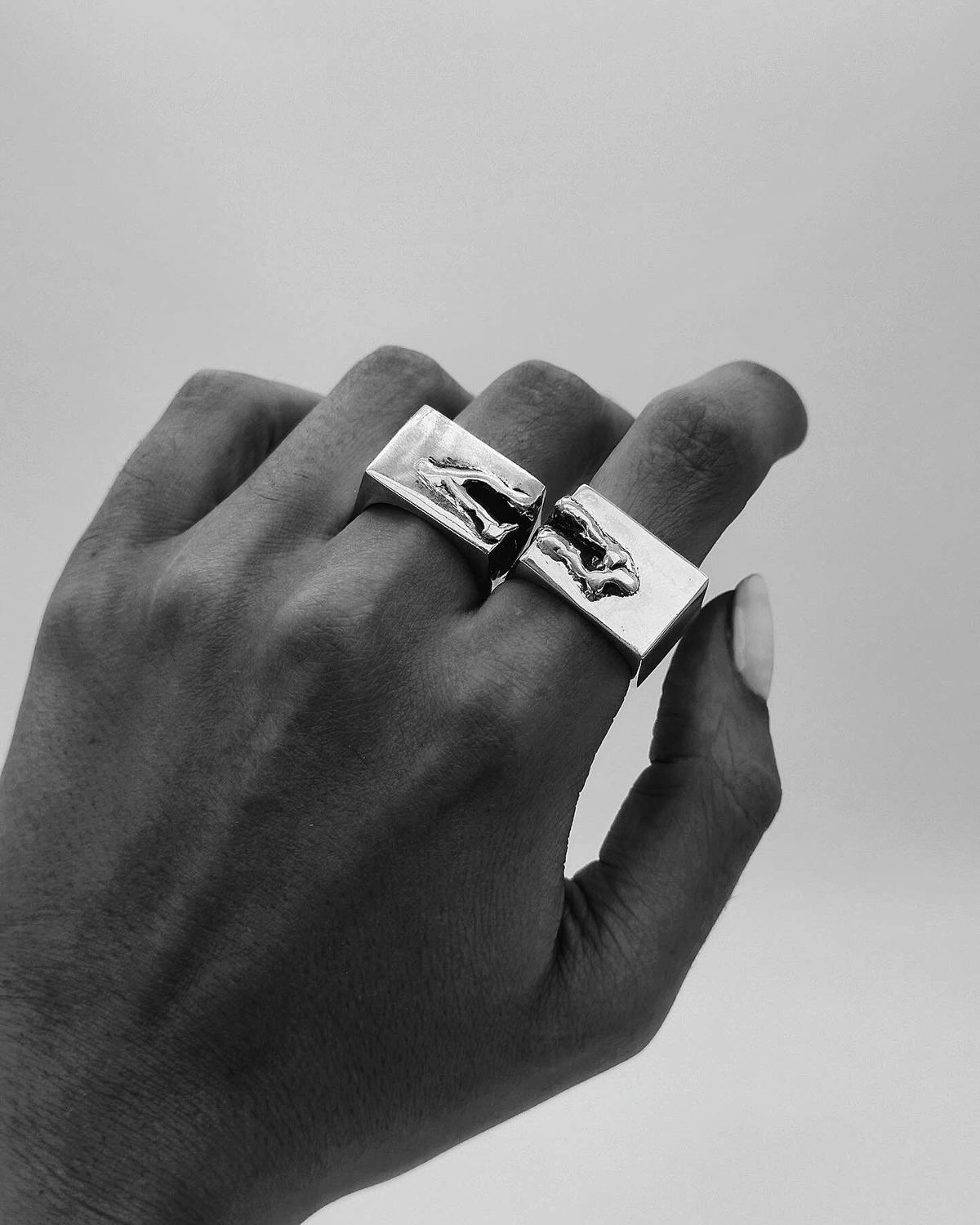 Black-and-white photograph of a hand wearing square rings, from the AGAPE collaboration.
