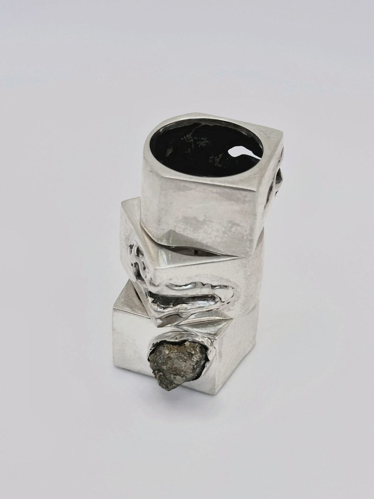 Stacked square silver rings, one with raw pyrite, on light grey.