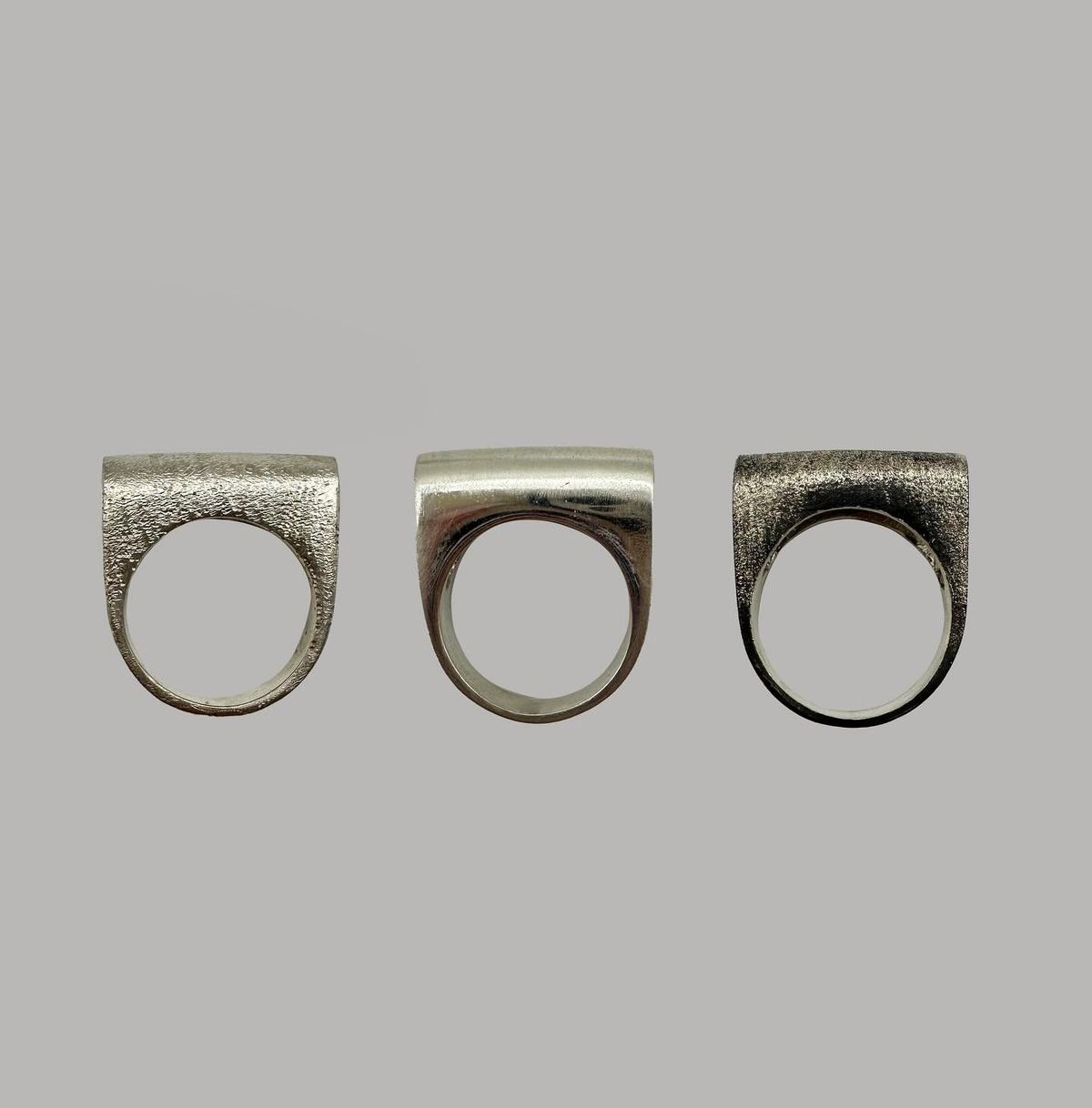 Tres anillos en forma de D con tres acabados, de la colaboración con AGAPE.