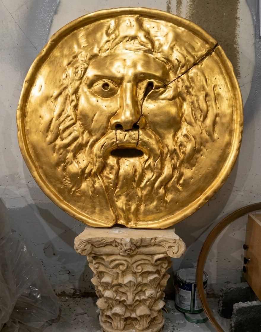 Gold-plated Bocca della Verità relief on a capital, in the workshop.