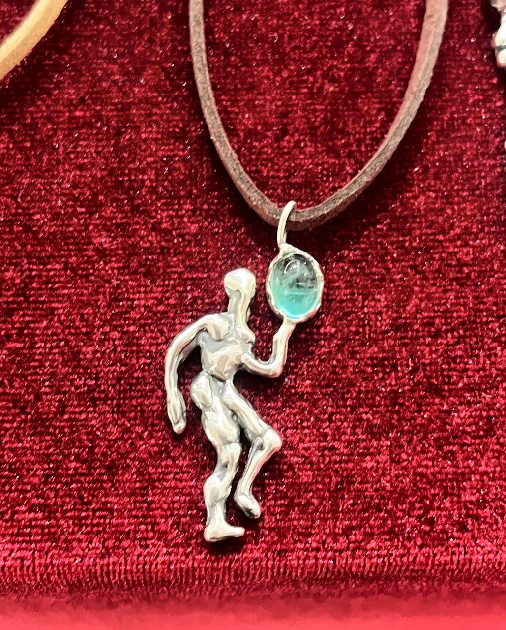 Silver dancer pendant with an aquamarine, on red velvet.