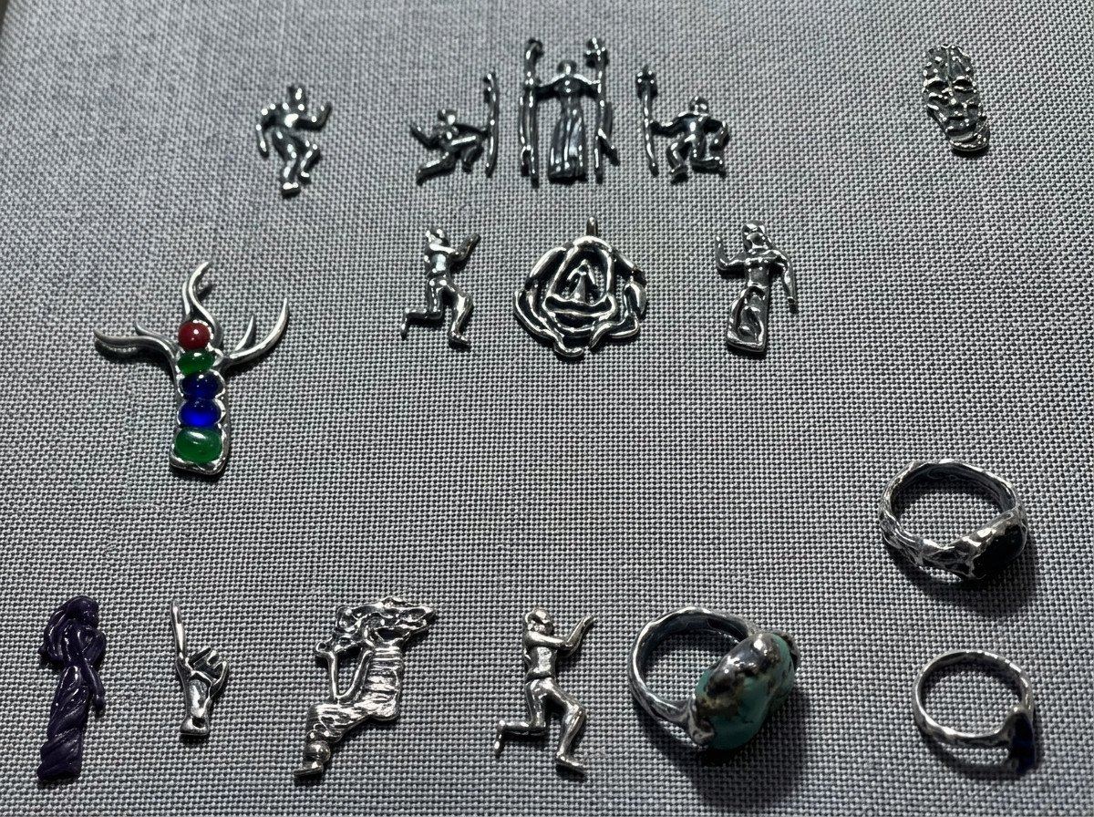 Las piezas de DavXmoM extendidas sobre una tela gris: figuras, anillos y colgantes.