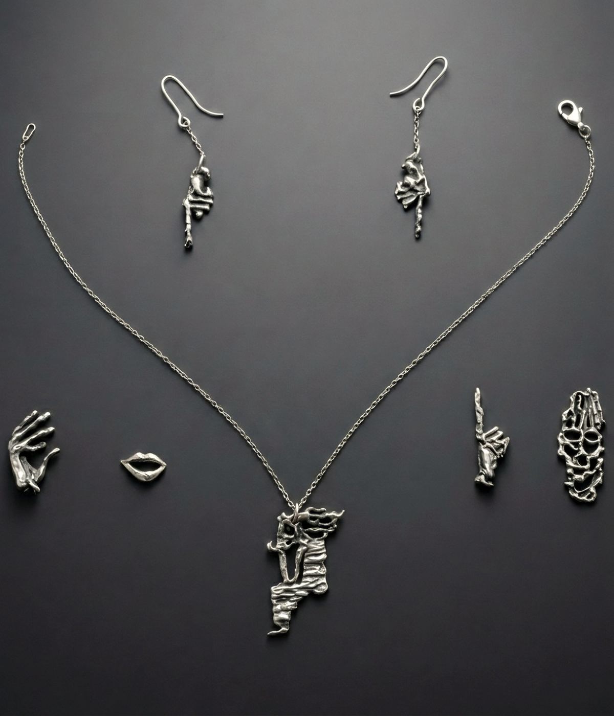 The DavXmoM set on grey: necklace, earrings, and hand and lip pendants.